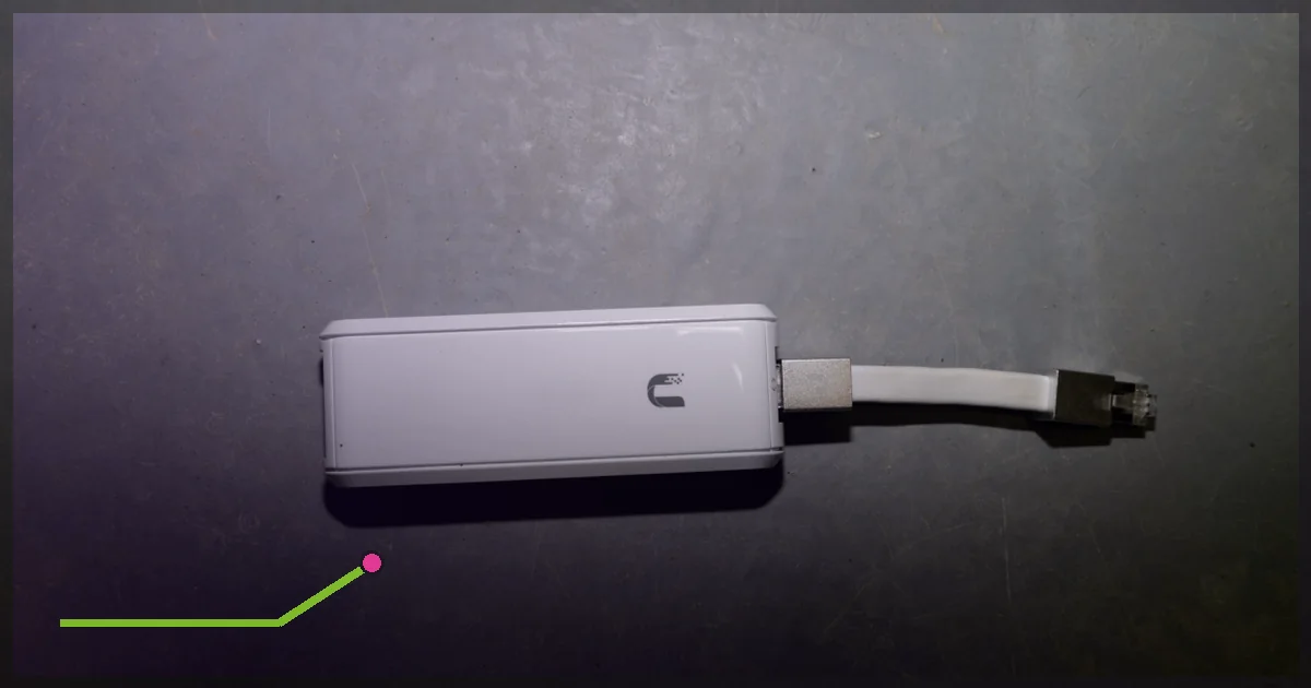 White network router connected by an Ethernet cable on a dark surface